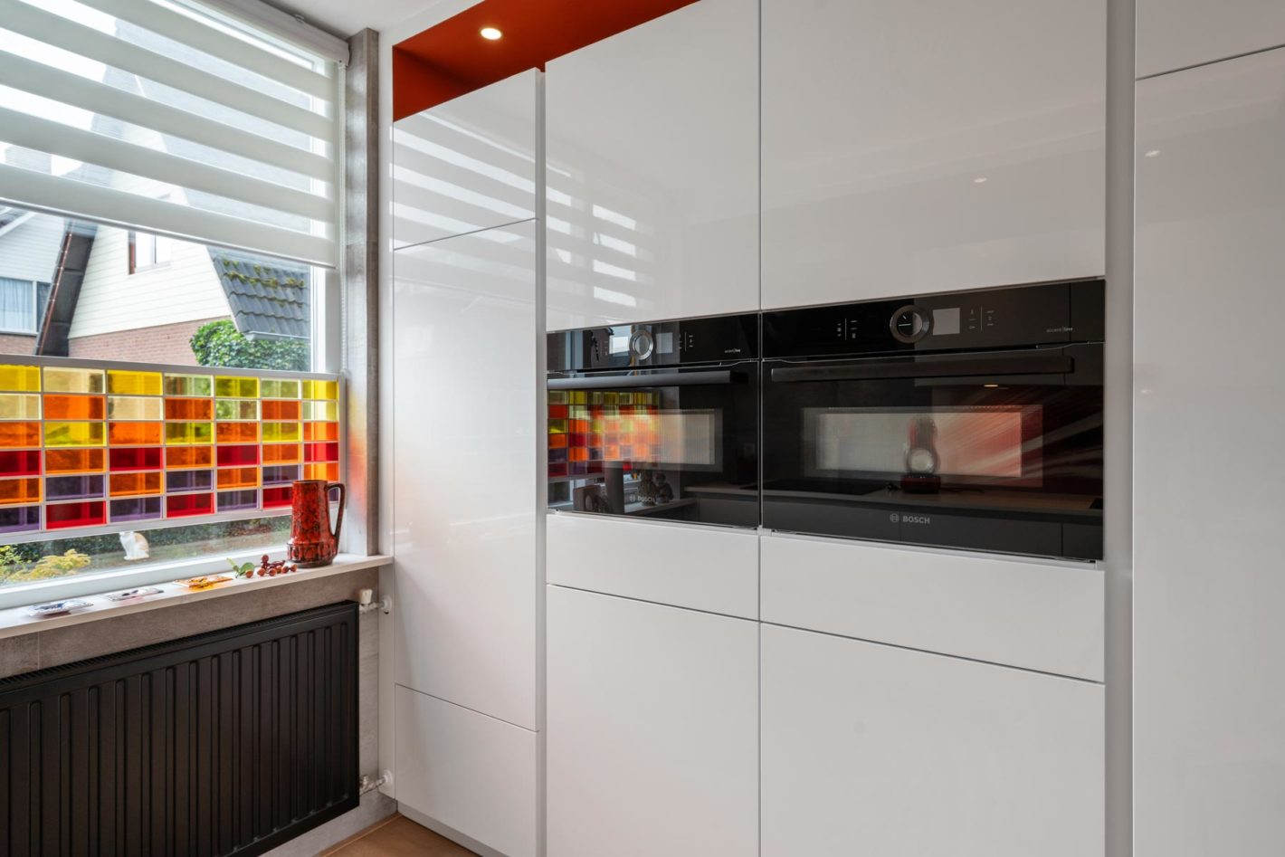 Moderne witte hoogglans keuken met rode kleuraccenten